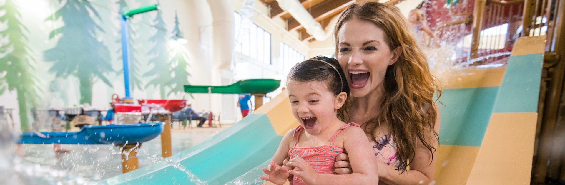 A kid and her mother enjoying a water slide at the the great wolf lodge and indoor water park